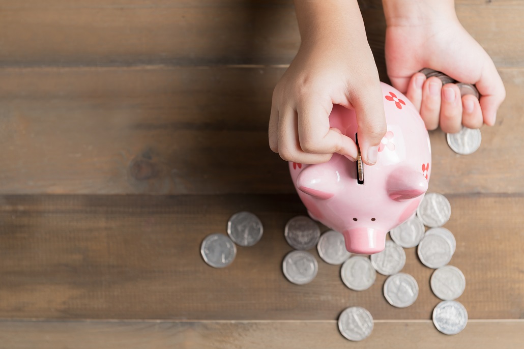 Hand placing coins in piggy bank