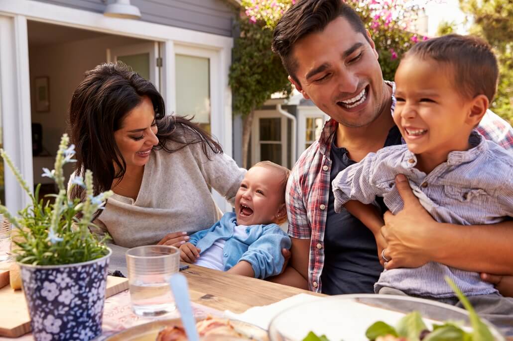 Family eating dinner, smiling because they are growing their college savings