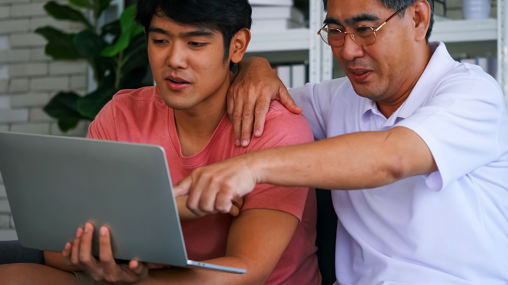father and son using computer to learn how to reduce college costs through scholarships and health insurance