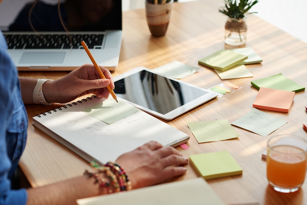 An individual writing at a desk planning for college