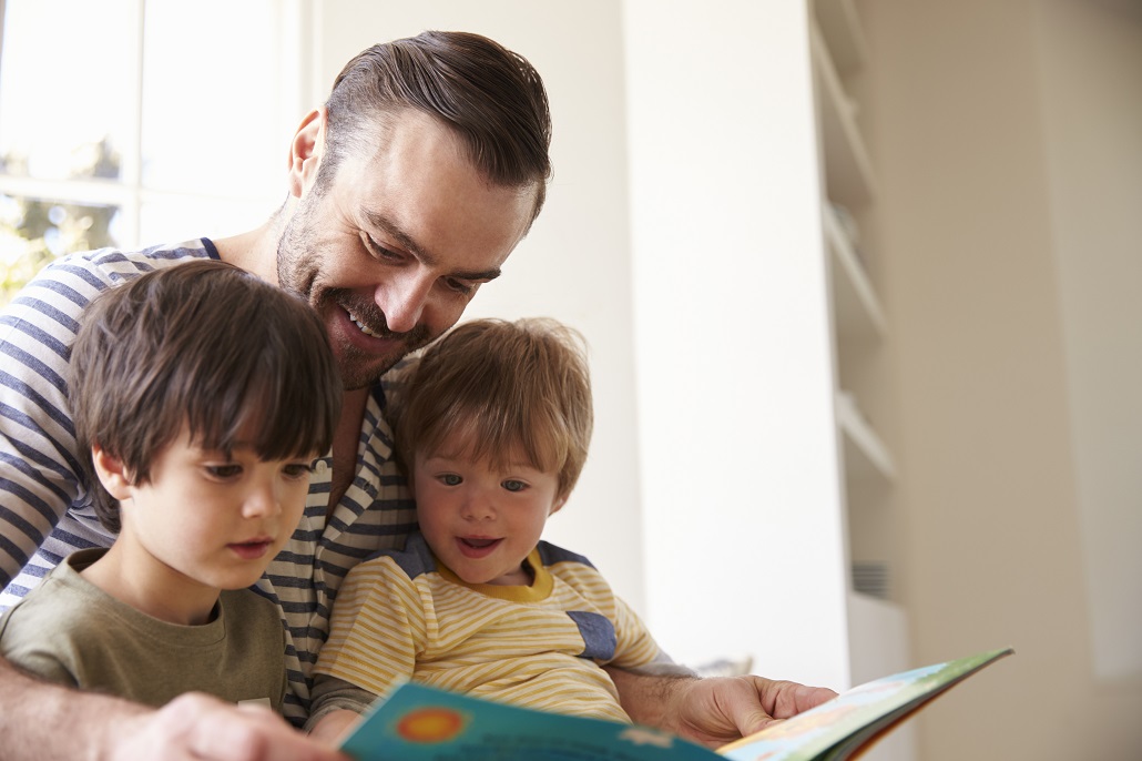 Father reading book to children in the summer