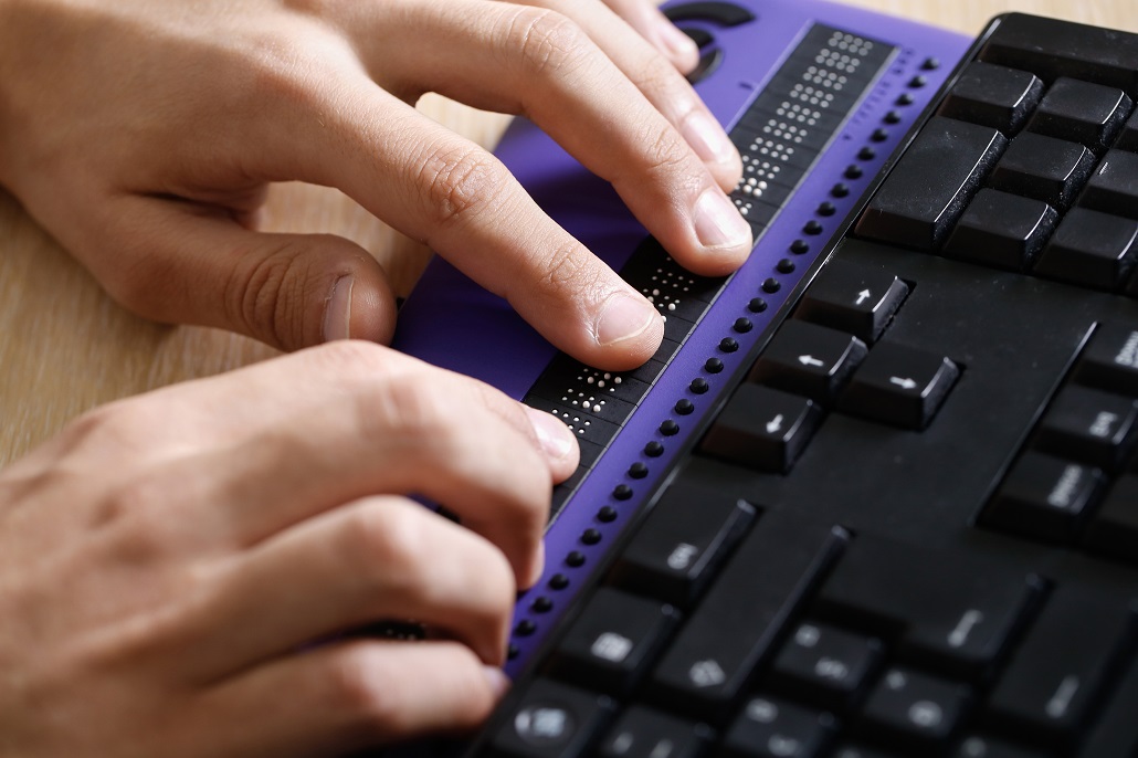 Student typing on braille keyword to search for scholarships for students with disabilities