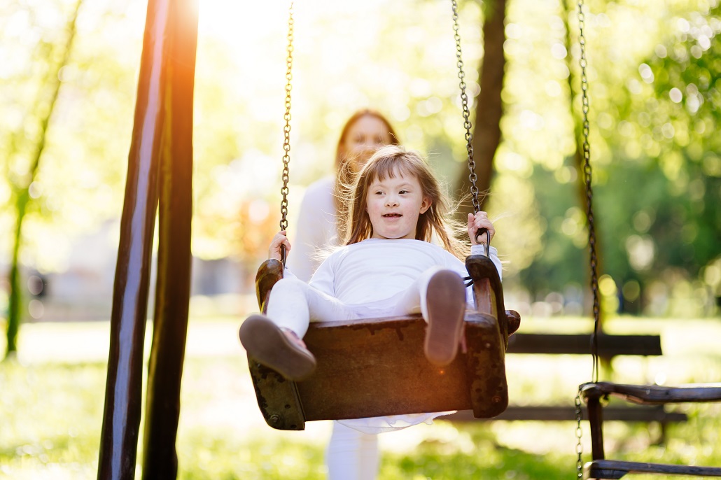 Mother pushing daughter on swing