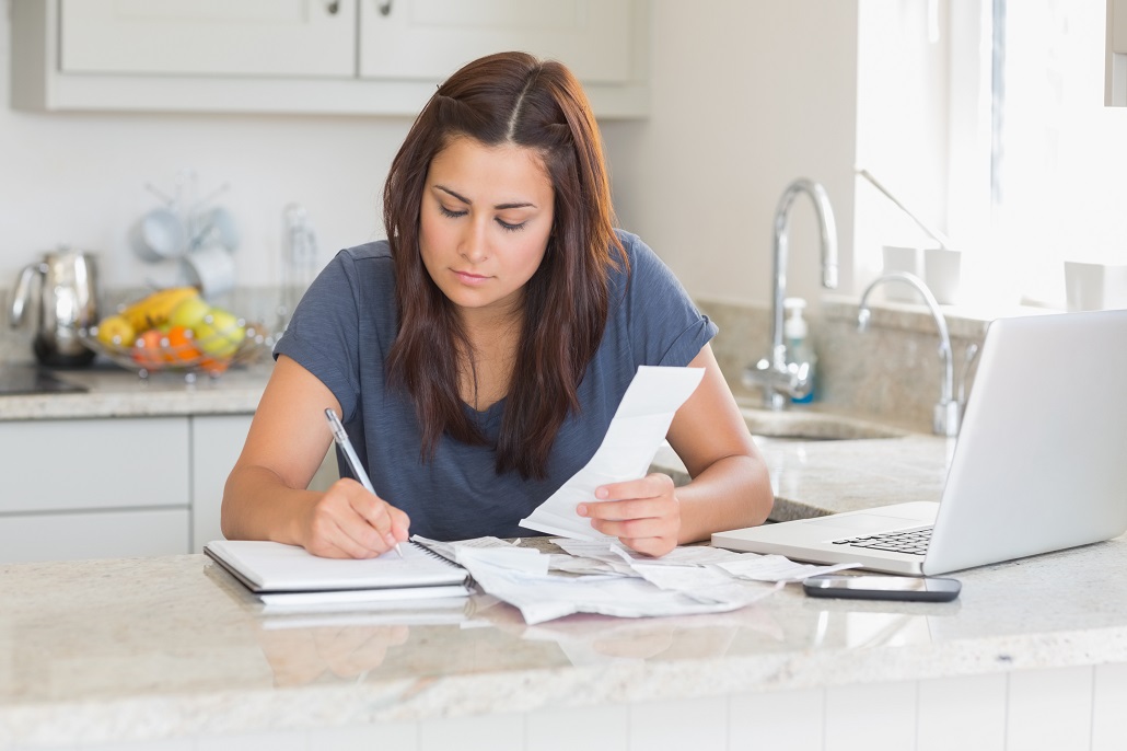 Student sitting in kitchen calculating her student loan refund