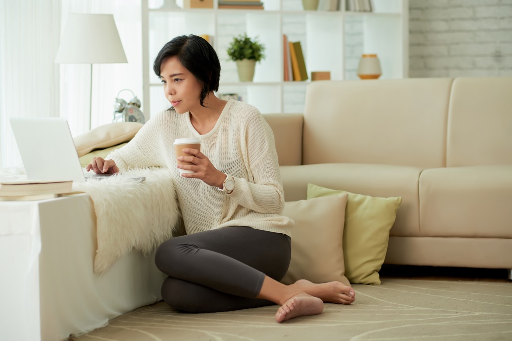 Woman completing the FAFSA on a laptop sitting next to a couch