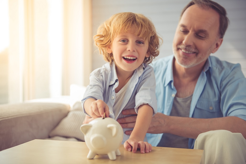 Father holding young son putting coins in a piggy bank to save in the U.Plan