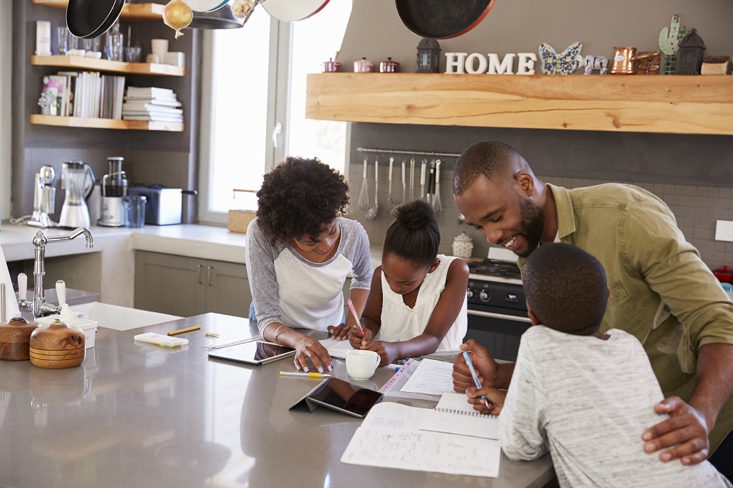 Parents helping children with homework in the kitchen