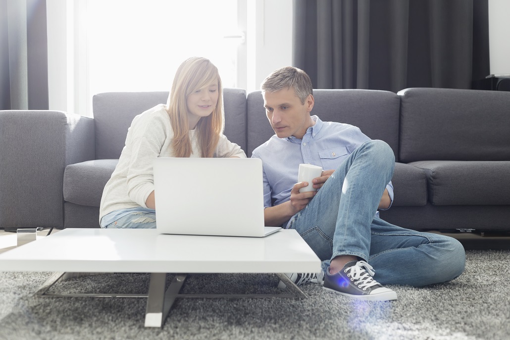 Father and daughter using laptop in living room