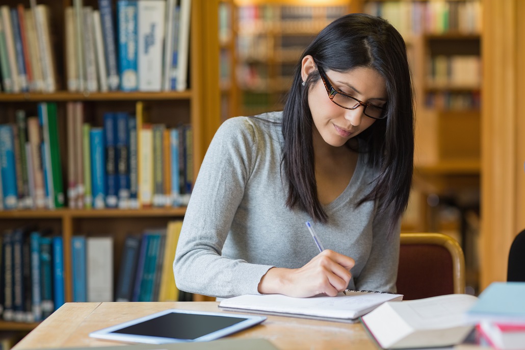 Student in library on laptop learning about Early Action and Early Decision