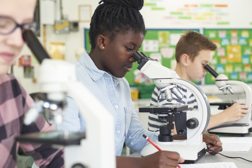 Student using a microscope in class to prepare for scholarships for the environmentally friendly