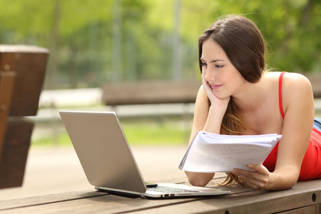 Teenage girl looking at MEFA Pathway website on a laptop outside