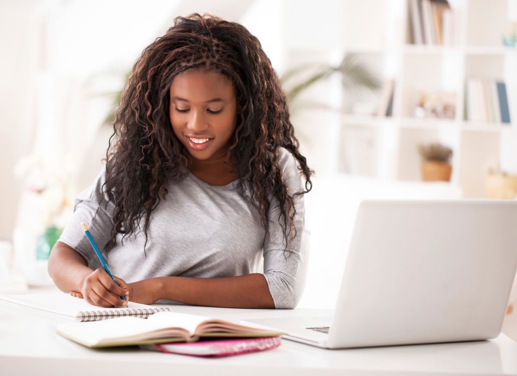 A high school junior working on a laptop preparing for college admissions this summer