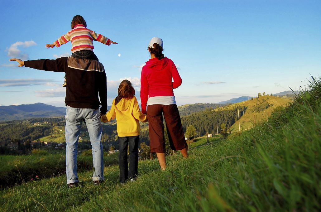 Family standing on a hill planning to save for college with 2 kids