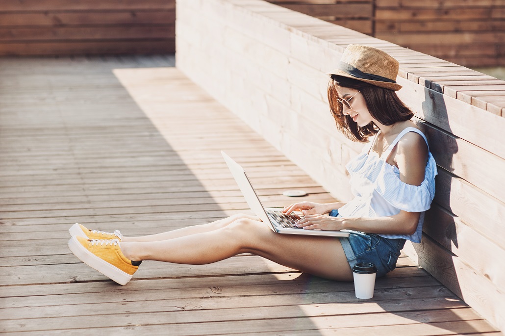 Girl using laptop on deck to search for scholarships for artists