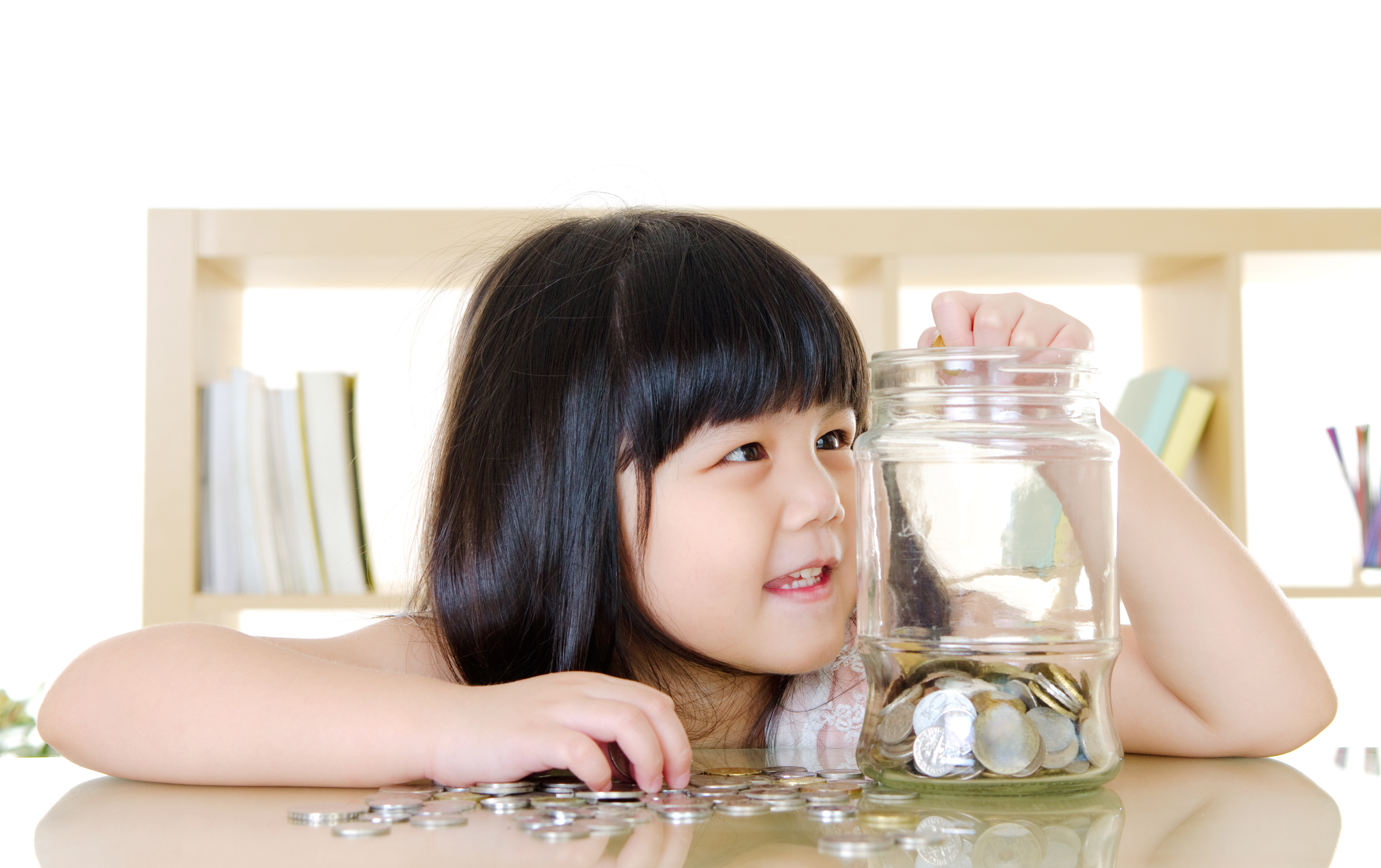 Young girl putting coins in a jar