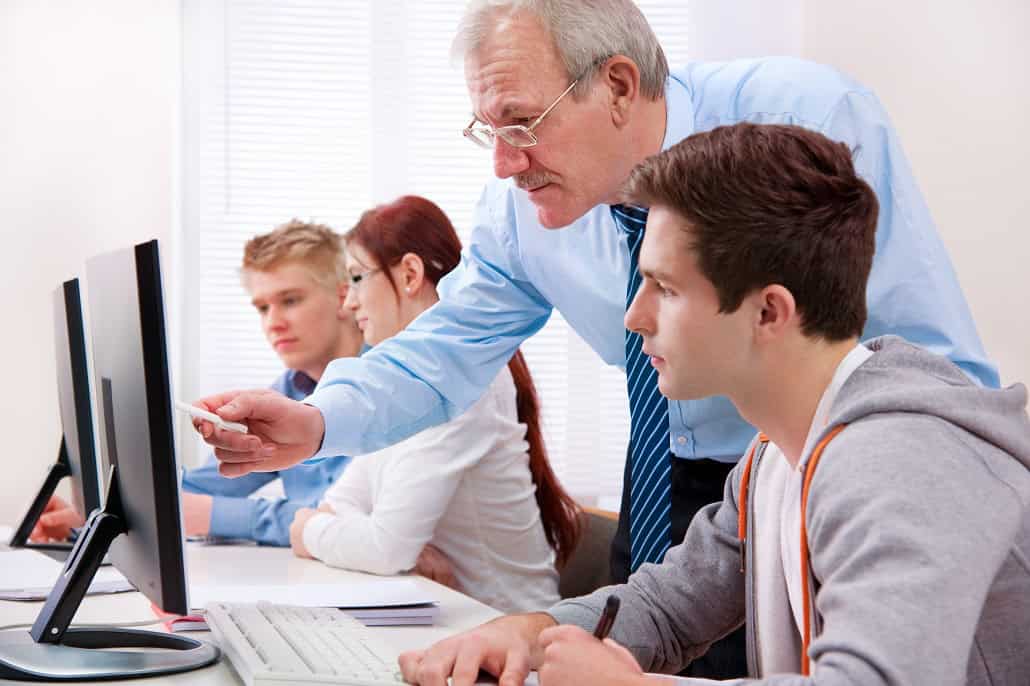 Teacher helping students at computers
