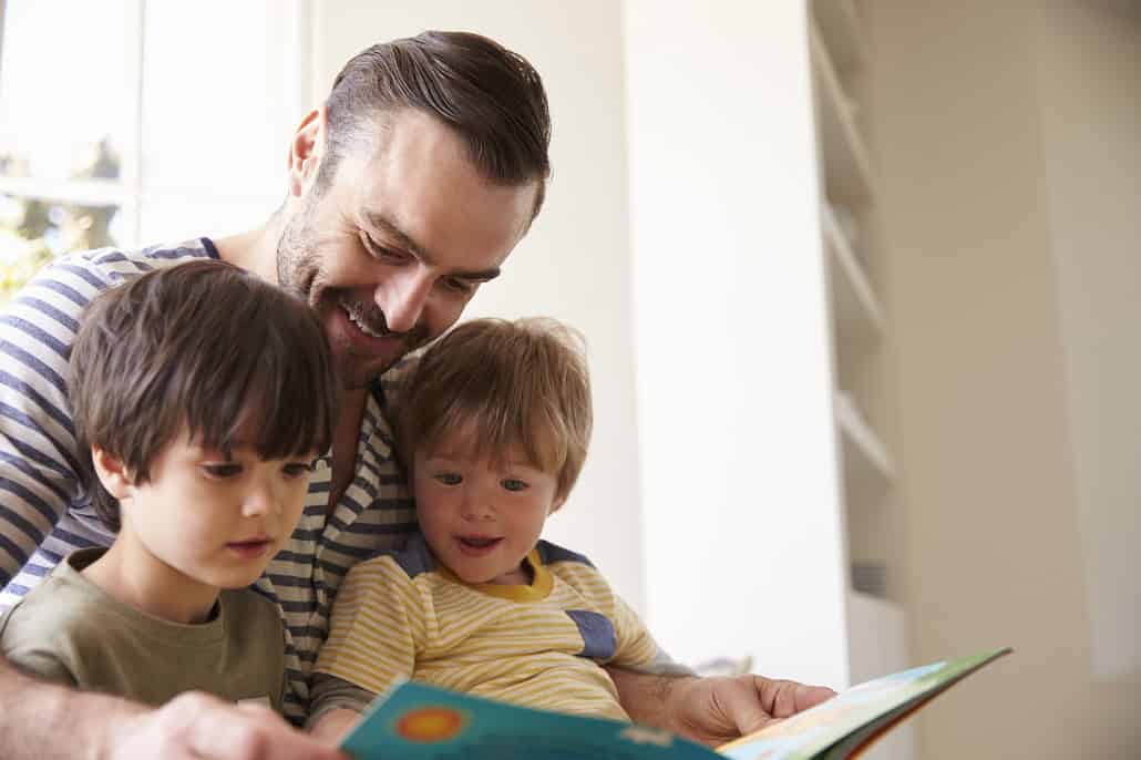 Father reading a book to two boys