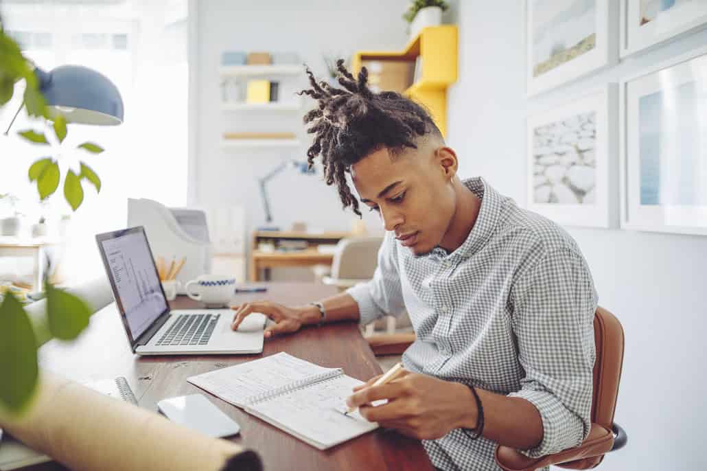 Teenager working at computer with a notebook